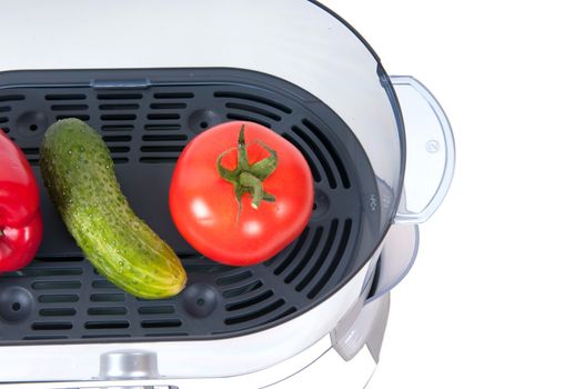 modern electric steamer with fresh cucumber and tomato on a white background