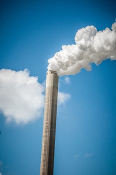 industrial chimney spewing smoke on blue sky