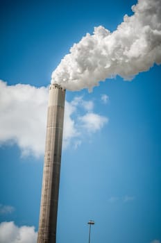 industrial chimney spewing smoke on blue sky