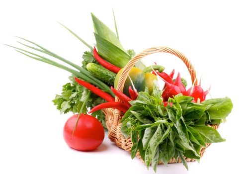Basket with Various Fresh Raw Vegetables and Greens and Big Red Tomato isolated on white background