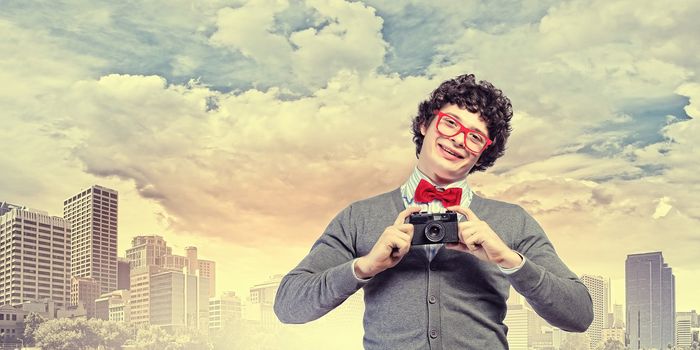 Image of young man in red tie with photo camera taking pictures