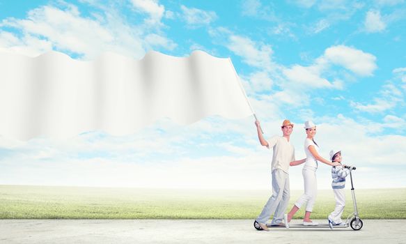 Image of happy young family riding on scooter pulling blank banner