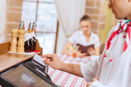 Image of handsome chef inserting card in terminal