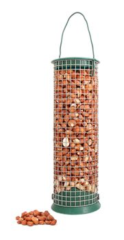 Bird feeder filled with peanuts and some nuts lying loose, isolated on a white background