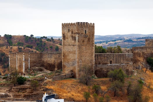 Fortified stone lookout tower with crenellations alongside a perimeter wall affording a view over the surrounding countryside and valley