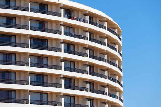 Exterior of a modern apartment block or hotel with a curved rounded design against a blue sky