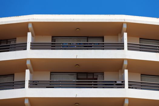 Exterior of a modern apartment block or hotel with a curved rounded design against a blue sky