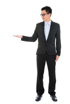 Full body portrait of young handsome smiling Asian business man hand showing blank empty space, standing isolated over white background