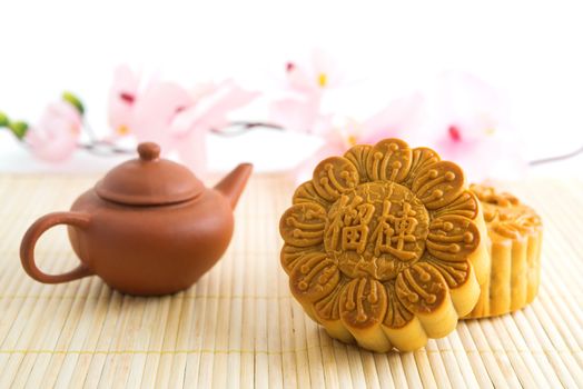 Chinese mid autumn festival foods. Traditional mooncakes on table setting with teapot. The Chinese words on the mooncakes means durian pure lotus paste, not a logo or trademark.