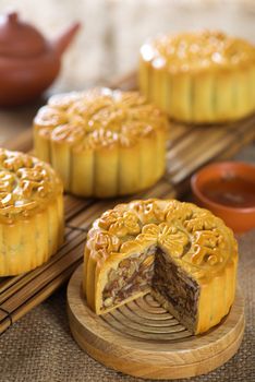 Chinese mid autumn festival foods. Traditional mooncakes on table setting with tea set.  The Chinese words on the mooncakes means assorted fruits nuts, not a logo or trademark.