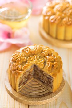 Traditional mooncakes on table setting with flower tea.  Chinese mid autumn festival foods. The Chinese words on the mooncakes means assorted fruits nuts, not a logo or trademark.