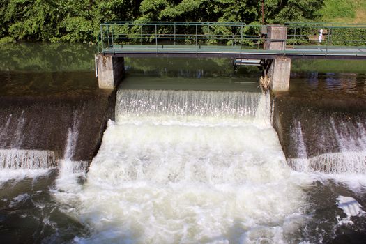 a dam retaining water from a swollen river with its bridge and waterfall