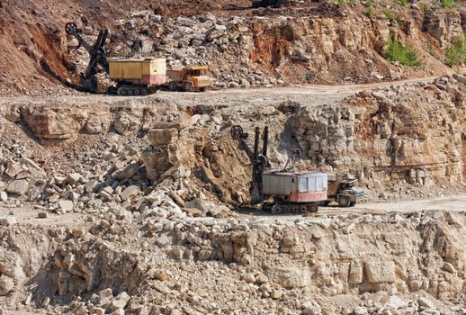 Big trucks and excavators work in career on mining