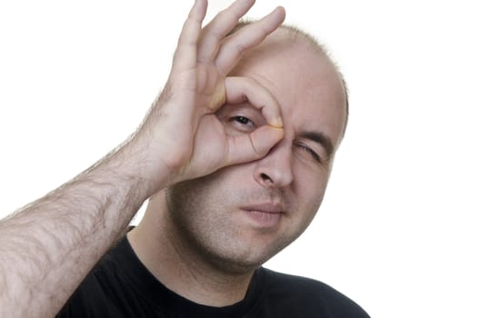 young man looking through his fingers like monocle on white background