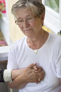 A grandmother with eyes closed clasping her grand daughters hand