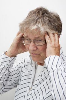 A senior citizen rubbing her temples to sooth head ache, isolated on white