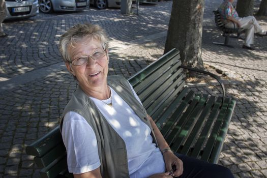 An active pensioner sitting on park bench in town square