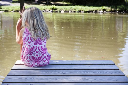 A little child sitting along on the river bank