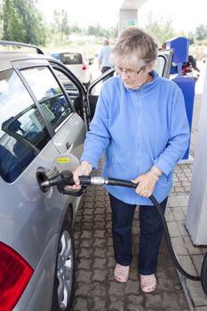 A senior femal filling up a car with diesel