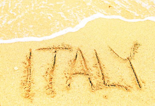 A warm tropical beach with Italy written in the sand 