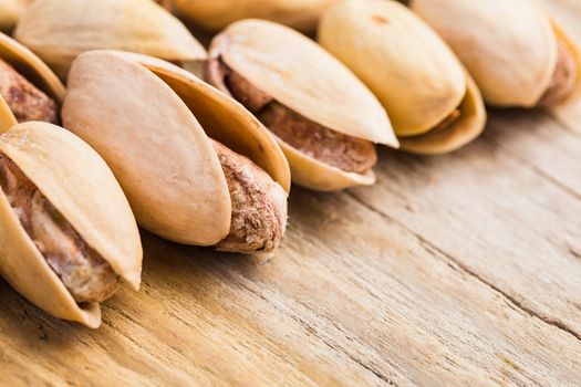 The pistachios heap against the background of wooden boards