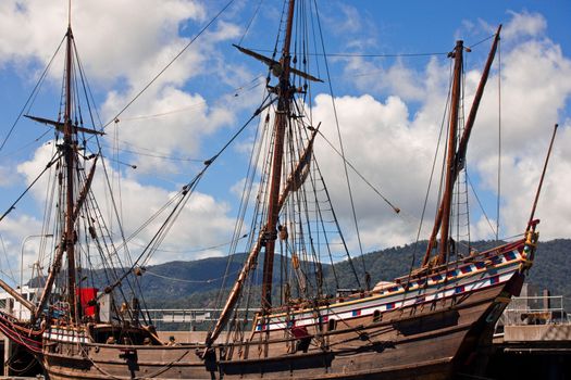 Three masted wooden schooner docked at a quay in harbour with its sails stowed away