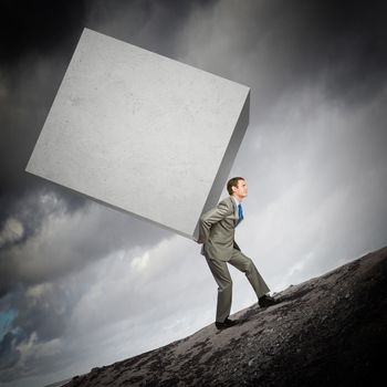 Image of businessman carrying big white cube on his back