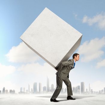 Image of businessman carrying big white cube on his back