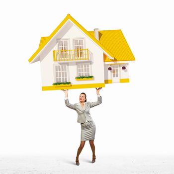 Image of businesswoman holding model of house above head