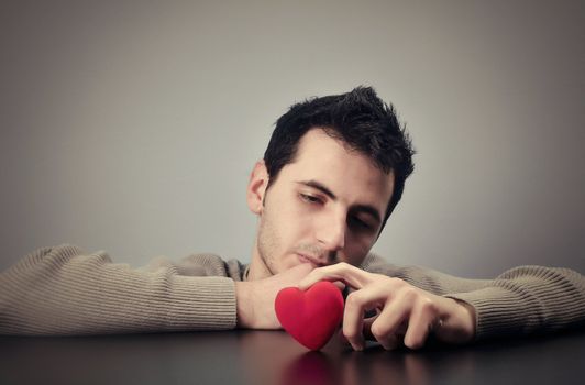 Young man looking at a heart with a sad look