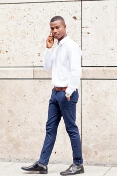 young successfil african businessman with mobilephone talking walking outdoor