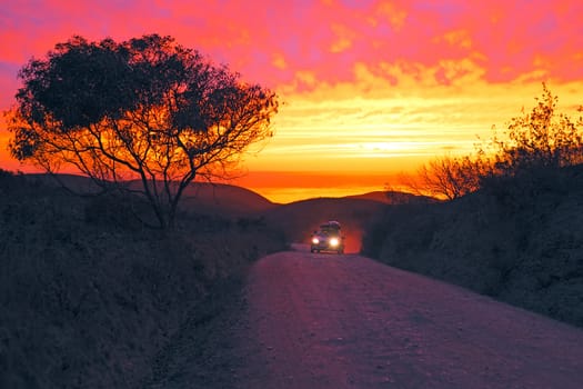 Car driving on a dirt road with an incredible sunset at the westcoast in Portugal
