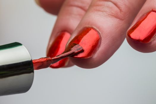 Painting female fingernails with red nail polish