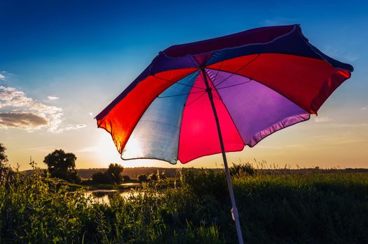 Colorful umbrella in the summer at sunset on a background of the sky