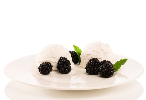 vanilla ice cream with blackberries and mint on a fawn plate with white background