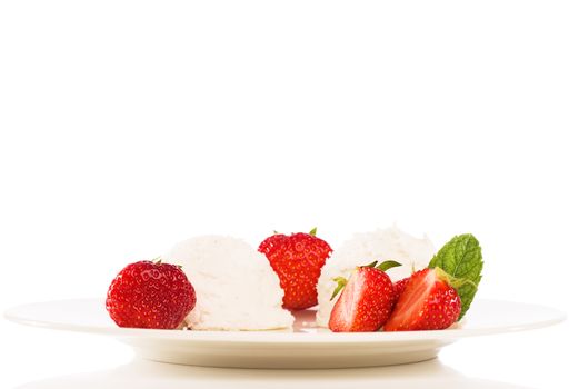 vanilla ice cream scoops on a fawn plate with strawberries and mint on white background