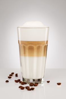 one original latte macchiato with coffee beans on gray background