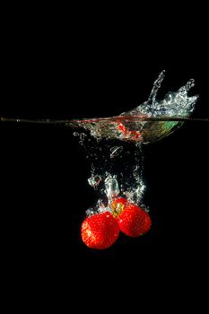 Colored red paprika in water splashes on black background