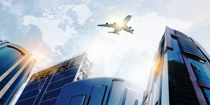 Plane flying above skyscrapers. Business travel concept