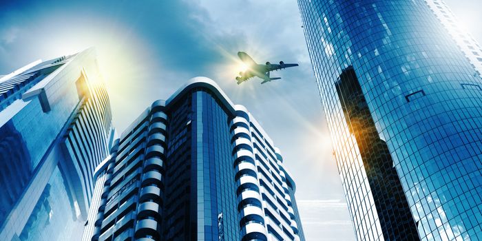 Plane flying above skyscrapers. Business travel concept