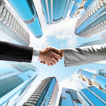 Close up image of hand shake against skyscrapers