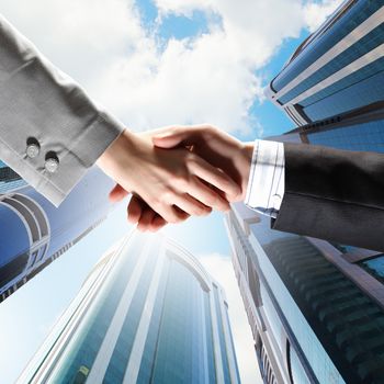 Close up image of hand shake against skyscrapers