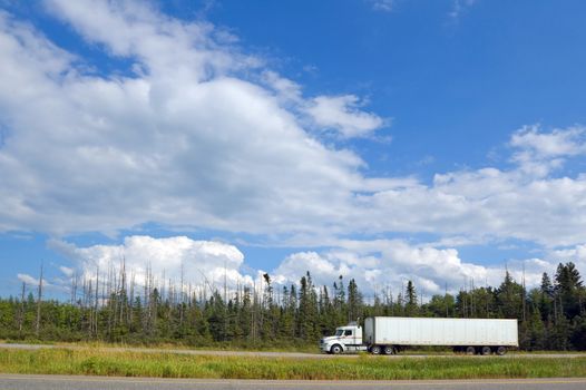 Cargo truck on Canada Highway under cloud blue sky