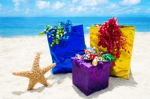 Starfish with gift box and two gift bags on sandy beach in sunny day- holiday concept