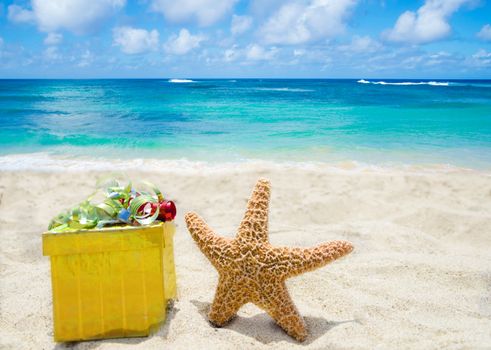 Starfish with yellow gift  box on sandy beach in sunny day- holiday concept