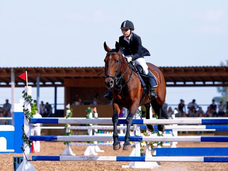 Equestrian sport. Show jumping. Overcoming of an obstacle. The sportswoman on a horse. The horsewoman on a red horse. Equestrianism. Horse riding. Horse racing. Rider on a horse.