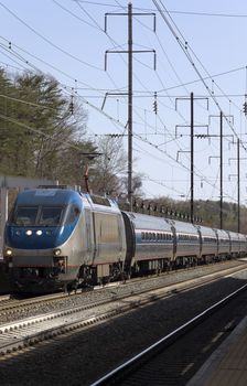 An electric train pulling into a station on rail road tracks