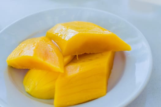Fruit. 4 sliced ������mango pieces on a white dish.