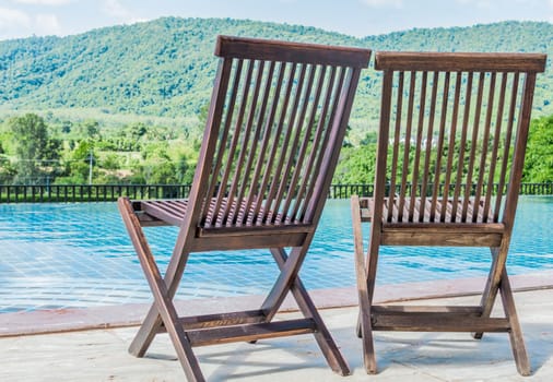 Wooden chair near the pool. With a mountain backdrop.