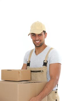 Handsome young workman with a confident smile carrying plain brown cardboard boxes, upper body isolated on white